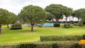Ein gepflegter Park mit alten Bäumen, einem Schwimmbecken und ordentlich geschnittenen Hecken.