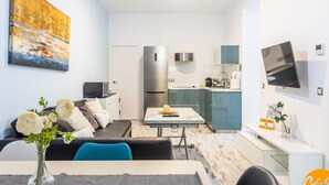 Um apartamento moderno com sala de estar, área de jantar e cozinha. Há uma televisão de tela plana na parede, um refrigerador e um micro-ondas.