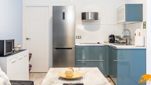 Uma cozinha compacta com geladeira de aço inoxidável, micro-ondas e pia.