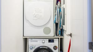 Uma área de lavanderia compacta com máquina de lavar frontal e secadora empilhada.