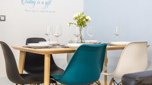 Uma área de refeições com uma mesa posta para quatro pessoas, cadeiras e uma parede com texto inspirador.