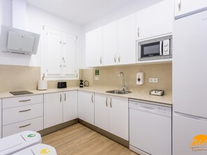 A modern kitchen with white cabinets, a microwave, a coffee machine, and a dishwasher. - Casa del Marinero by Livework (Cádiz)
