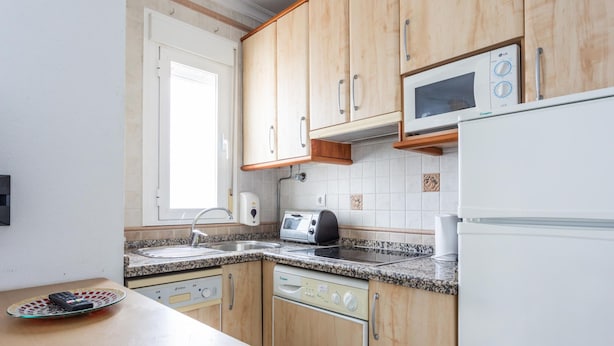 A kitchen with wooden cabinets, a microwave, a toaster, and a dishwasher. - Apartamento Sue o by C diz Time (Conil de la Frontera)