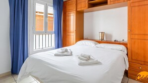 A bedroom with a bed, wooden wardrobe, and a window with curtains. - Apartamento Sue o by C diz Time (Conil de la Frontera)