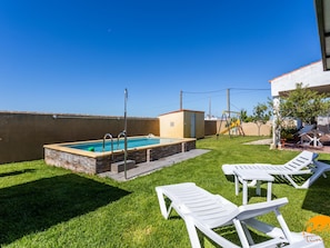 Ein Garten mit Swimmingpool, zwei Liegestühlen und einer kleinen Spielzone.