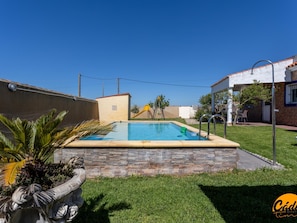 Ein Swimmingpool mit Steinbord, einer Palme und einer kleinen Spielzone mit einer Rutsche.