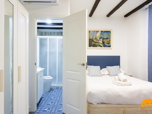Ein Schlafzimmer mit Bett, einem Bild und einem durchgegangenen Tür sichtbaren Badezimmer.