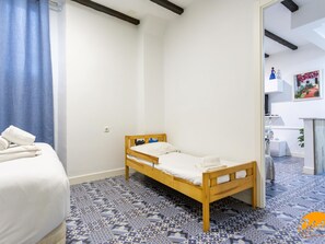 Una habitación con una cama de madera, un suelo con estampado azul y una pared blanca.