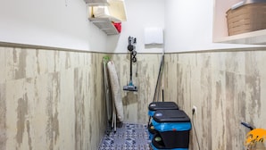 Een smalle badkamer met een douche, een handdoekhouder, een toilet en een klein plankje met een mandje.