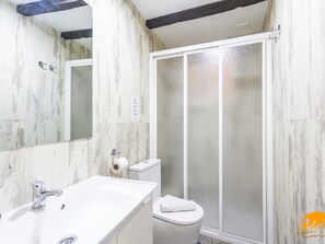 Ein Badezimmer mit Waschbecken, Spiegel, Toilette und Duschkabine aus Glas.