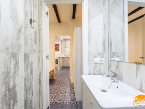 A bathroom with a white sink, a mirror, and a patterned floor. - Posada del Barrio by Livework (Cádiz)