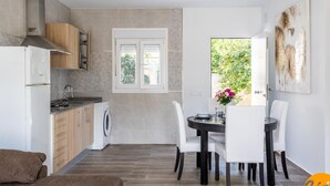 Uma cozinha moderna com forno embutido, máquina de lavar e área de refeições com mesa e cadeiras.