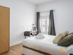 Ein Hotelzimmer mit einem Bett, einem Schreibtisch mit Stuhl und einem Fenster mit Vorhängen.