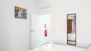Une chambre d’hôtel avec un lit, un tableau, un extincteur et un miroir.