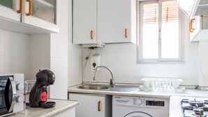 A compact kitchen with white cabinets, a built-in dishwasher, a sink, and a stove. - Teresa Uno by Cadiz Time (Cádiz)
