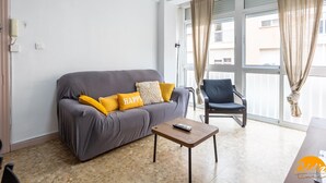 A modern living room with a grey sofa, yellow cushions, a wooden coffee table, and a blue armchair. - Teresa Uno by Cadiz Time (Cádiz)