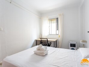 A hotel room with a bed, a desk, a chair, a window with curtains, a wall-mounted air conditioner, and a bedside lamp. - Teresa Uno by Cadiz Time (Cádiz)