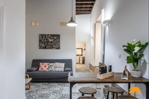Ein modernes Wohnzimmer mit grauem Sofa, Couchtisch und Essbereich mit Holztisch und Stühlen.