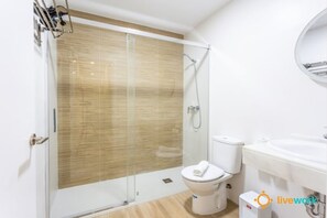 A modern bathroom with a glass-enclosed shower, a toilet, and a sink. - C diz Living by Livework (Cádiz)