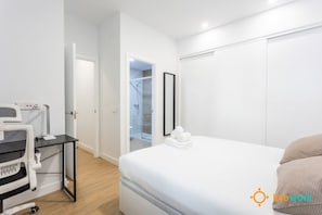 A modern bedroom with a bed, a desk with a computer, and a walk-in closet. - C diz Living by Livework (Cádiz)
