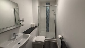 Un baño moderno con lavamanos, inodoro y cabina de ducha de vidrio.