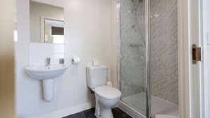 Ein Badezimmer mit weißem Waschbecken, Toilette und Duschkabine.