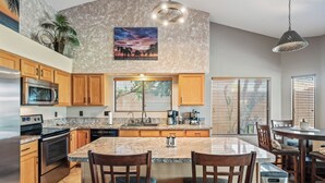 A modern kitchen with wooden cabinets, a large island, stainless steel appliances, and a view of the outdoors through the window. - SANCTUARY IN THE SUN, 
great location to go or stay (Mesa)