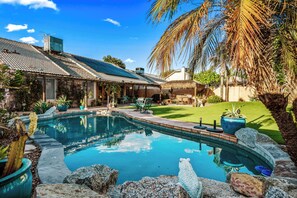 A pool with a curved edge, surrounded by rocks and potted plants. - SANCTUARY IN THE SUN, 
great location to go or stay (Mesa)