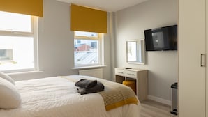 A hotel room with a bed, a bedside table, a TV, a window, and a wardrobe. - Relaxing Retreat in Cheltenham (Cheltenham)