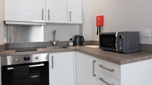 A modern kitchen with white cabinets, stainless steel appliances, a kettle, and a microwave. - Relaxing Retreat in Cheltenham (Cheltenham)