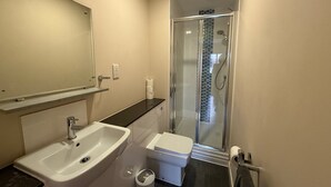 A bathroom with a sink, toilet, and glass-enclosed shower. - Cosy 2-bedroom Flat close to Royal Holloway (London)