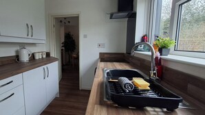 Et moderne køkken med hvide skabe, en træbordplade, indbygget ovn og et vindue med udsigt til det fri.