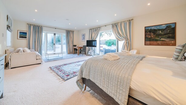 A spacious bedroom with a large bed, a desk, and a television. - Jeeves Hideaway - sleeps 2 guests  in 1 bedroom (Old Hunstanton)