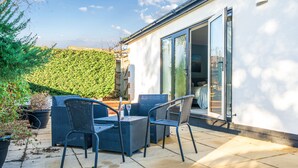 An outdoor patio with wicker furniture and a glass door leading to a covered area. - Jeeves Hideaway - sleeps 2 guests  in 1 bedroom (Old Hunstanton)