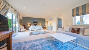A spacious bedroom with a large bed, a sitting area with a sofa, and a dining table. - Jeeves Hideaway - sleeps 2 guests  in 1 bedroom (Old Hunstanton)