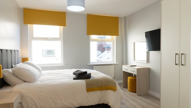 Un dormitorio con cama, mesita de noche, armario y televisión.