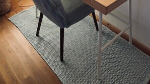 A wooden dining table with a blue cushion, a woven placemat, and a glass candle holder. - The Master's Suite [In the heart of the Borgo] (Bienno)