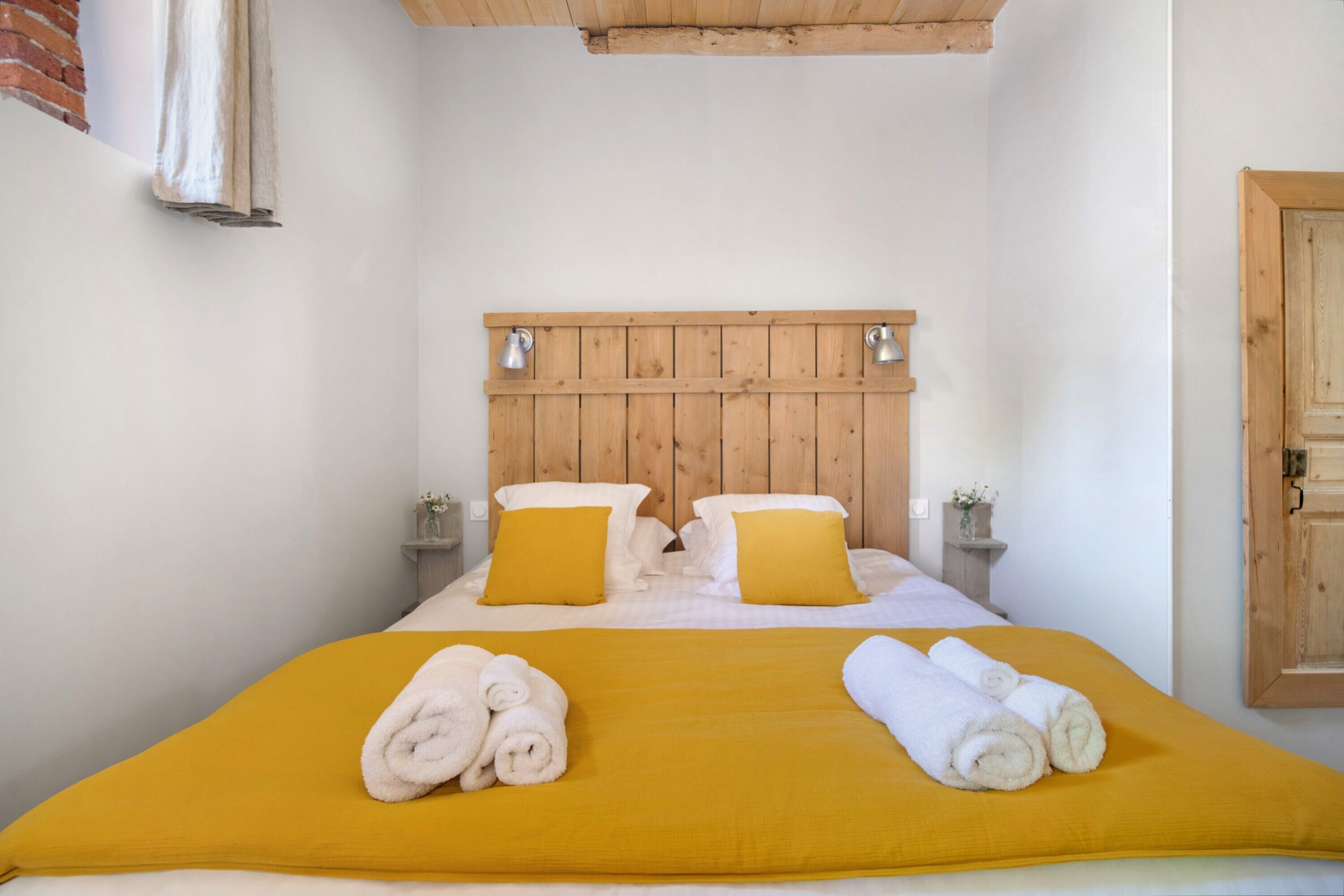 A bed with a wooden headboard, two bedside tables with lamps, and a yellow bedspread.