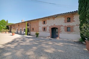 A building with a brick facade, multiple windows, and a gravel driveway.
