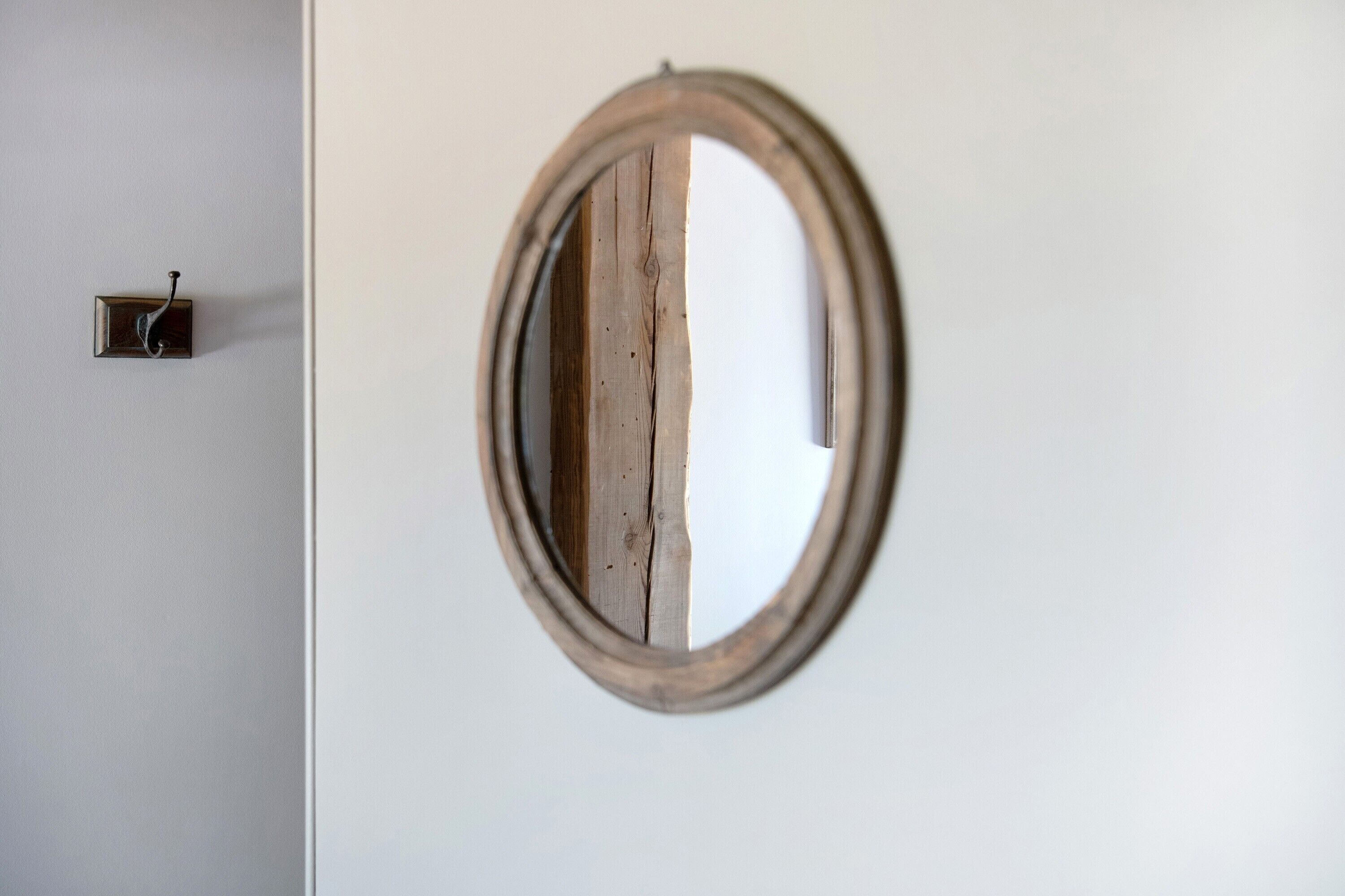 A round mirror with a wooden frame mounted on a white wall.