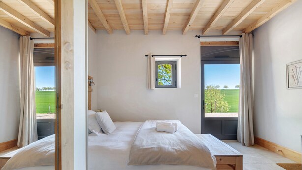 A bedroom with a large bed, a small window, and a view of a green field. - Bed and Breakfast 'Chambre 'Cousin Paul'' with Shared Pool, Wi-Fi and Air Conditioning (Verfeil)