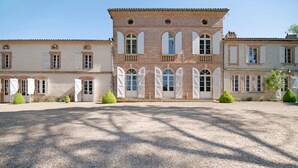 A large building with a symmetrical facade, multiple windows with shutters, and a gravel courtyard. - Bed and Breakfast 'Chambre 'Cousin Paul'' with Shared Pool, Wi-Fi and Air Conditioning (Verfeil)