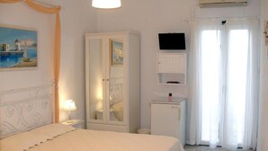 A bedroom with a bed, a wardrobe, a television, and a window with curtains. - ARETHOUSA (Milos)