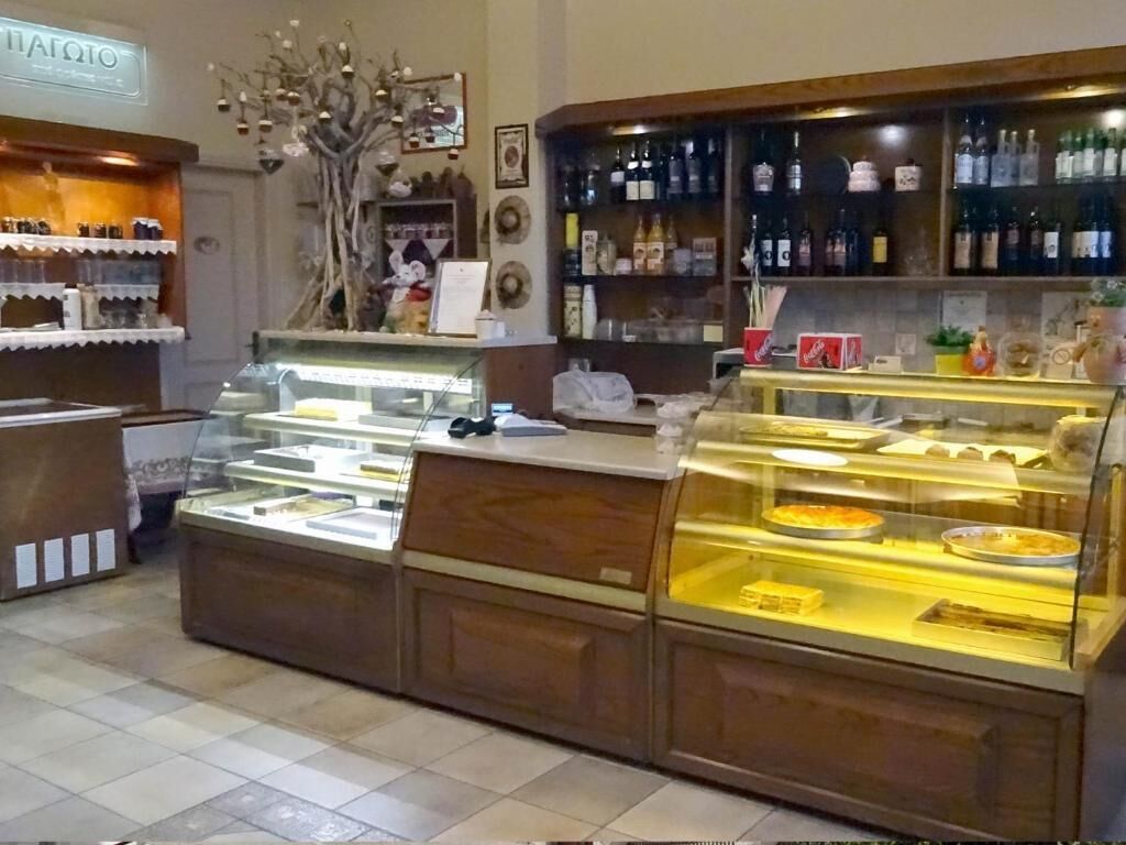 A bakery counter with display cases, a selection of bottles on shelves, and a decorative tree.
