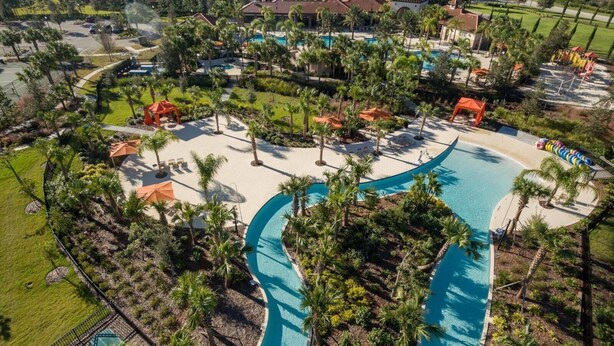 Ett semesterhotell med en stor pool, palmer och utsikt över de omgivande husen.