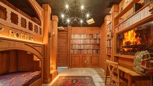 Eine gemütliche Bibliothek mit Holzbögen, einem Kamin und einem Bett mit einem 'Harry Potter'-Kopfstück.