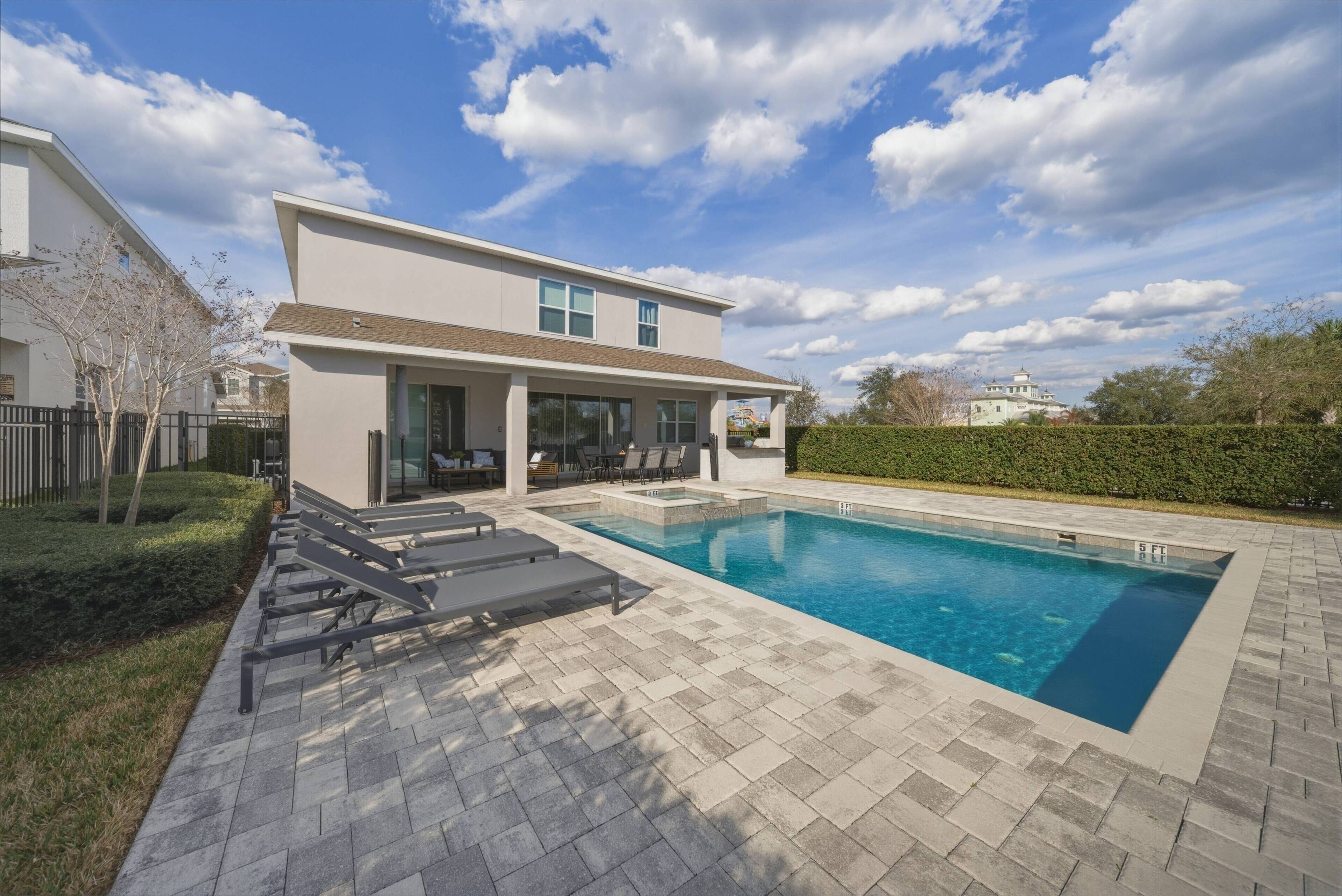A modern two-story house with a swimming pool, outdoor seating, and a well-maintained garden.