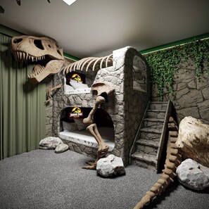 A themed room with a dinosaur skeleton, a bed, and a stone archway. - 9BR house sleeps 22 with pool table (Kissimmee)