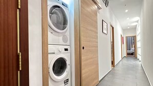En hall med inbyggd tvättmaskin och torktumlare, trädörrar och ett klinkergolv.