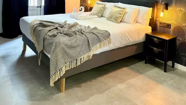 Una camera da letto moderna con un letto grande, una parete decorata e un comodino con una lampada.